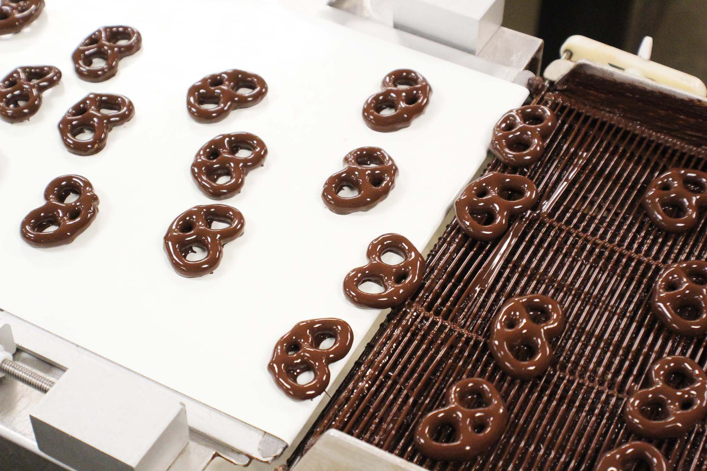 Dark chocolate covered pretzels on conveyer belt